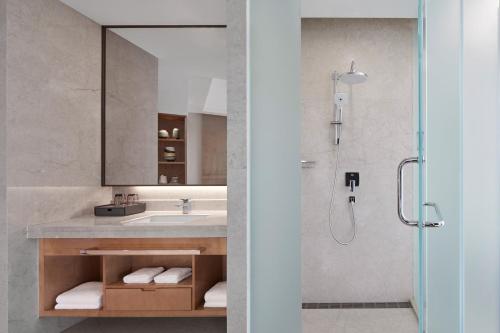 ein Bad mit einem Waschbecken und einer Dusche mit einem Spiegel in der Unterkunft Sheraton Shaoxing Shangyu in Shaoxing