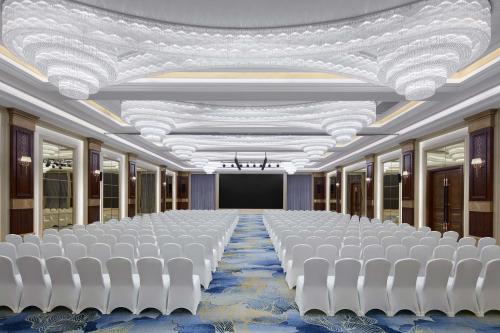a conference room with white chairs and a stage at Sheraton Shaoxing Shangyu in Shaoxing