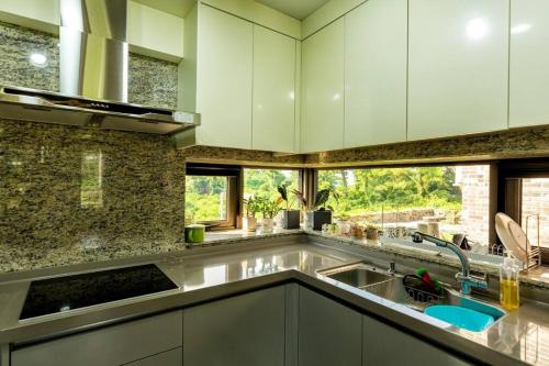 a kitchen with white cabinets and a sink at Jeju Sunshine Pension in Jeju