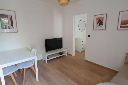 - un salon blanc avec une table et une télévision dans l'établissement Appartement tout equipé proche Paris/Orly, à Choisy-le-Roi