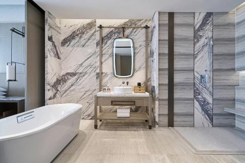 a bathroom with a tub and a sink and a mirror at Wuxi Marriott Hotel Lihu Lake in Wuxi