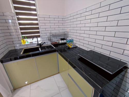 a kitchen with black counter tops and a sink at Lembah Saerah Resort in Kangar