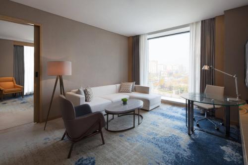 a living room with a white couch and a table at Courtyard by Marriott Zhengzhou Airport in Zhengzhou