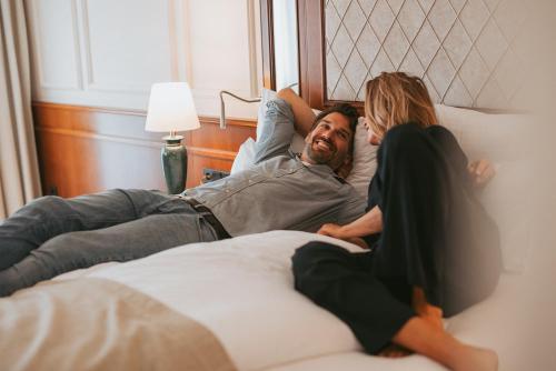 a man and a woman laying on a bed at MANNI das Hotel in Mayrhofen