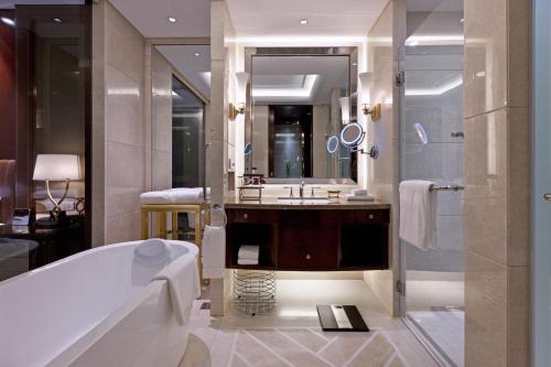 a bathroom with a tub and a sink and a mirror at Sheraton Changzhou Wujin Hotel in Changzhou