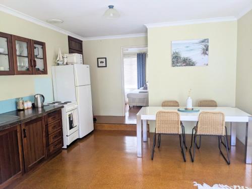 uma cozinha com uma mesa e um frigorífico branco em Bright & breezy chalet close to town & beach em Dunsborough