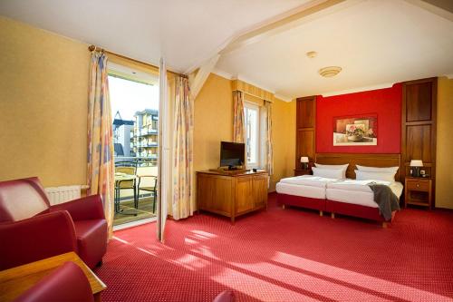 een slaapkamer met een bed en een tv en een bank bij Strandvilla Viktoria - Anbau vom Strandhotel Preussenhof in Zinnowitz