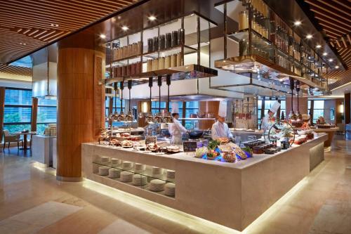 a restaurant with a counter with people preparing food at Courtyard by Marriott Hangzhou Qianjiang in Hangzhou