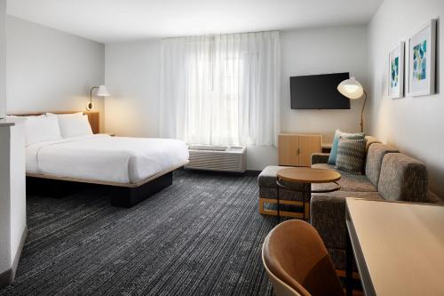 um quarto de hotel com uma cama e um sofá em TownePlace Suites Dulles Airport em Sterling