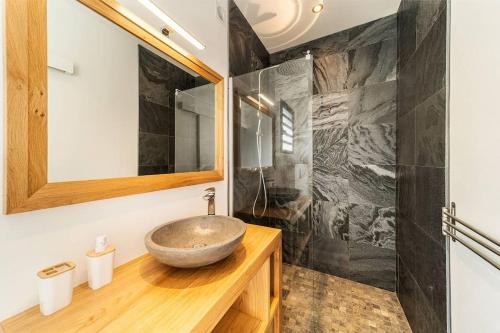 uma casa de banho com um lavatório de pedra e um espelho. em Ville d'Elsa-Magnifique villa avec piscine et vue mer à Grand-Bois em Saint-Pierre