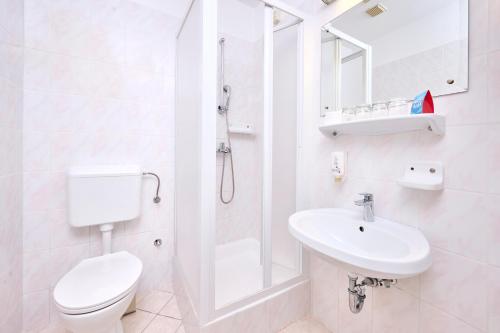 a white bathroom with a toilet and a sink at Apartments Galijot Plava Laguna in Poreč