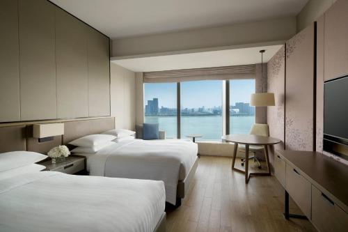 Cette chambre comprend deux lits, une table et une fenêtre. dans l'établissement Hangzhou Marriott Hotel Qianjiang, à Hangzhou