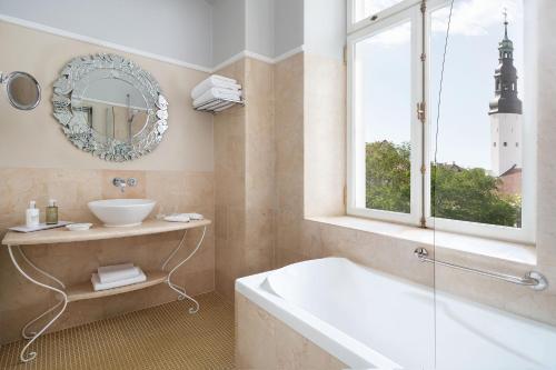 a bathroom with a tub and a sink and a mirror at Hotel Telegraaf, Autograph Collection in Tallinn