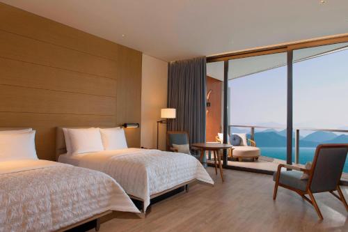 a hotel room with two beds and a large window at Le Méridien Xiaojing Bay in Huizhou