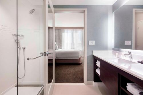 a bathroom with a shower and a sink and a bed at Residence Inn by Marriott Boston Watertown in Watertown