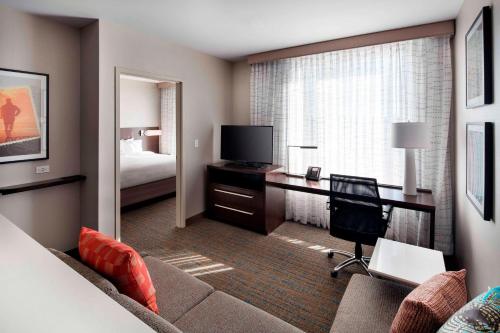 a hotel room with a couch and a bedroom at Residence Inn by Marriott Boston Watertown in Watertown