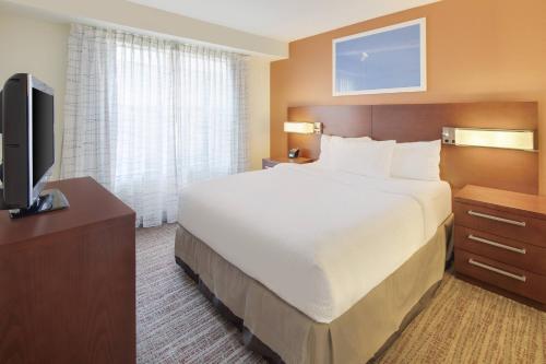 a hotel room with a bed and a flat screen tv at Residence Inn Indianapolis Airport in Indianapolis
