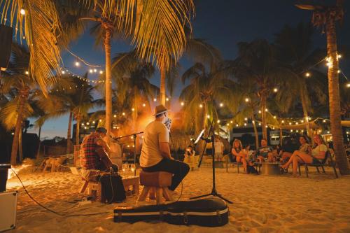 dos hombres sentados en una playa por la noche en Blue Bay Curaçao Golf & Beach Resort, en Willemstad
