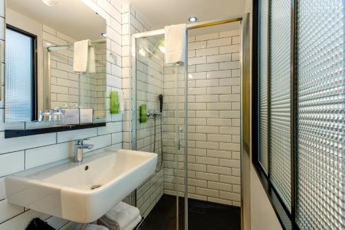 La salle de bains blanche est pourvue d'un lavabo et d'un miroir. dans l'établissement Le Cardinal - Belle-Ile-en-Mer, à Sauzon