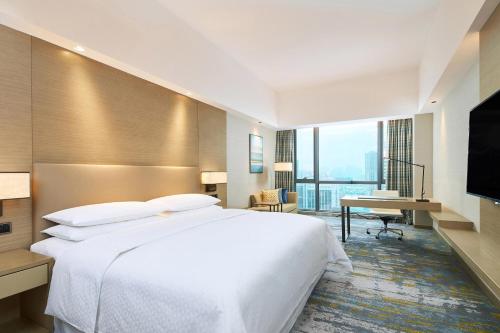 a hotel room with a large white bed and a desk at Four Points by Sheraton Jiaxing in Jiaxing