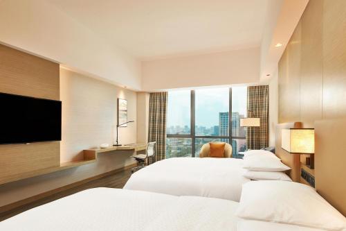 a hotel room with two beds and a flat screen tv at Four Points by Sheraton Jiaxing in Jiaxing