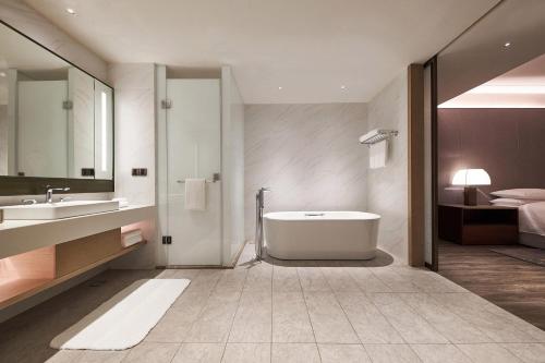 a bathroom with a tub and a sink and a bed at Four Points by Sheraton Jiaxing in Jiaxing