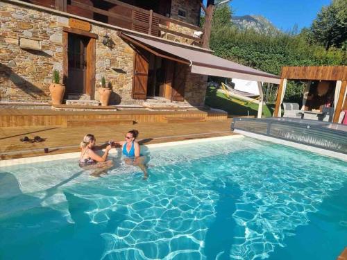 Deux femmes sont assises dans une piscine dans l'établissement gîte à la montagne au calme, à Bézins-Garraux