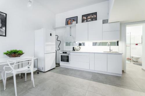 een witte keuken met een tafel en een koelkast bij Apartmany Albrechtice in Albrechtice nad Orlicí