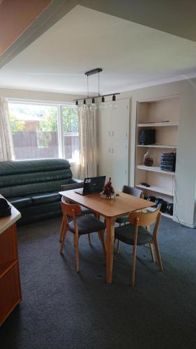 uma sala de estar com uma mesa e um sofá em Cabin style / sleepout em Christchurch