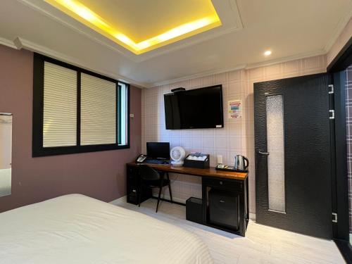 a bedroom with a bed and a desk with a television at Jjak motel in Changwon