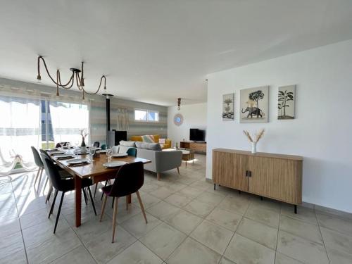 une salle à manger et un salon avec une table et des chaises dans l'établissement Refuge côté Mer by Melrose, à Asnelles
