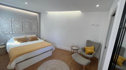 a small bedroom with a bed and a chair at C-10 Vegueta Apartment - Private Rooftop Pool in Las Palmas de Gran Canaria