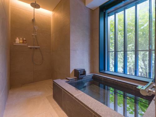 a bathroom with a tub and a shower with a window at Niseko Kyo in Niseko