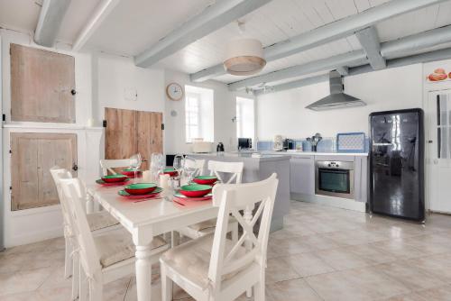 - une cuisine avec une table blanche et des chaises blanches dans l'établissement Maison Rétaise pour 6 à La Flotte en Ré, à La Flotte