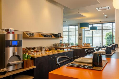 a large kitchen with a long line of counters and tables at ibis Styles Saumur Gare Centre in Saumur