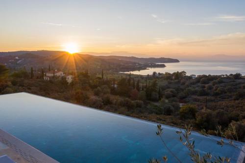 a pool with the sunset in the background at Villa Alchaca - New Magnificent Villa with Infinity Pool & Tennis in Kilada
