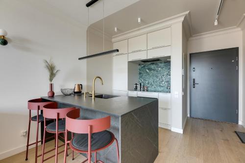a kitchen with red bar stools and a counter at Chlebova River View by Grand Apartments in Gdańsk