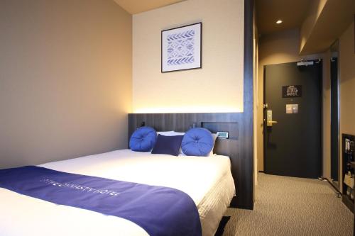 a bedroom with a large bed with blue pillows at Dynasty Hotel & Resort Osaka in Osaka