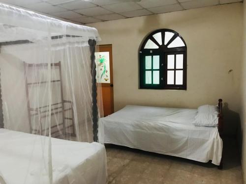 1 dormitorio con 2 camas y ventana en Senani Villa, en Hungama