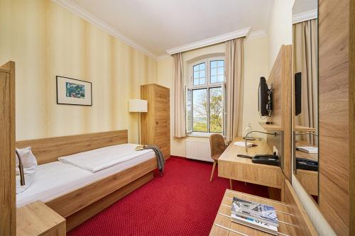 ツィノヴィッツにあるStrandhotel garni Kormoranのベッドとデスクが備わるホテルルームです。