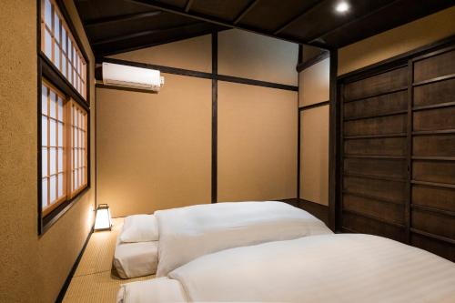 een slaapkamer met 2 bedden en een licht op de vloer bij Rinn Premium Machiya Koki in Kyoto