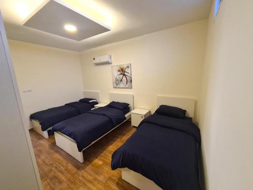 trzy łóżka w pokoju z niebieską pościelą w obiekcie Zoom Chalets w mieście Amman