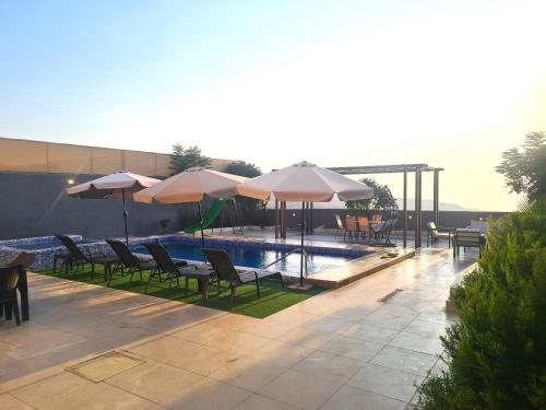 una piscina con tavoli, sedie e ombrelloni di Zoom Chalets ad Amman