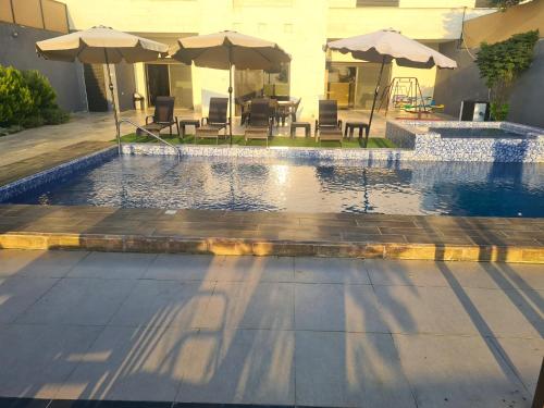 a swimming pool with tables and umbrellas and chairs at Zoom Chalets in Amman