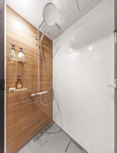 a shower in a bathroom with a wooden wall at Apartment Hotel 11 Shinsaibashi 2 in Osaka