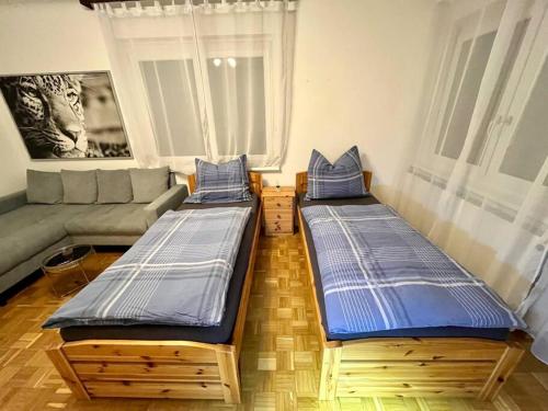 2 Betten im Wohnzimmer mit Sofa in der Unterkunft Wohnung Nähe LKH und der Med Uni in Graz