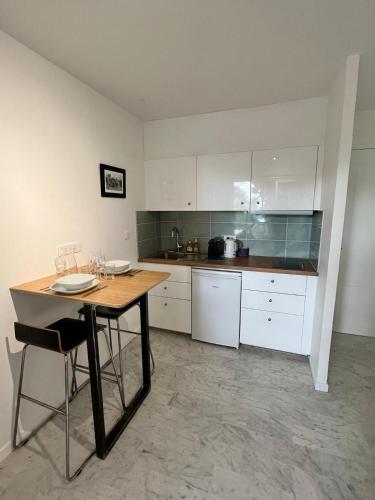 een keuken met witte kasten en een houten tafel bij Les Appartements De Lina By LG Immo -Studio Maya - Self Check-In - in La Grande-Motte