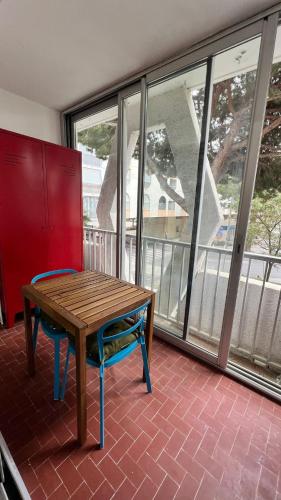 een houten tafel en een stoel in een kamer met ramen bij Les Appartements De Lina By LG Immo -Studio Maya - Self Check-In - in La Grande-Motte