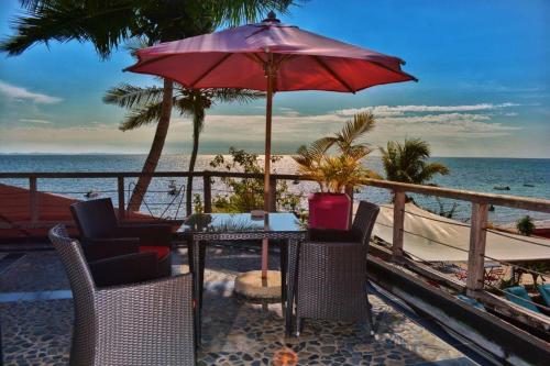 einen Tisch und Stühle mit Sonnenschirm am Strand in der Unterkunft Hôtel Résidence Sarimanok in Ambatoloaka