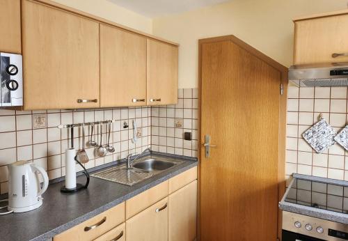 a kitchen with wooden cabinets and a sink at Gästehaus Nietmann_ Ferienwohnung 6 in Altenau